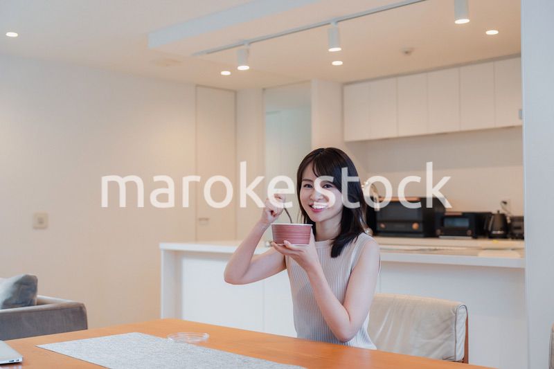 家でコンビニ弁当を食べる若い女性