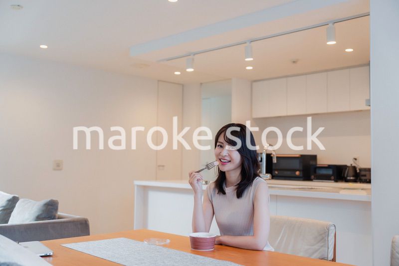 家でコンビニ弁当を食べる若い女性