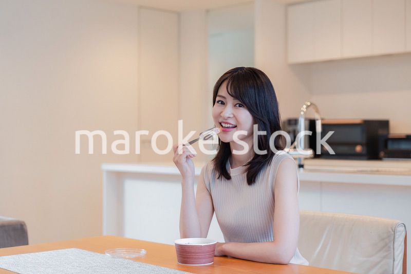 家でコンビニ弁当を食べる若い女性