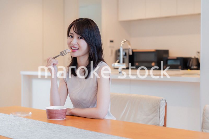 家でコンビニ弁当を食べる若い女性