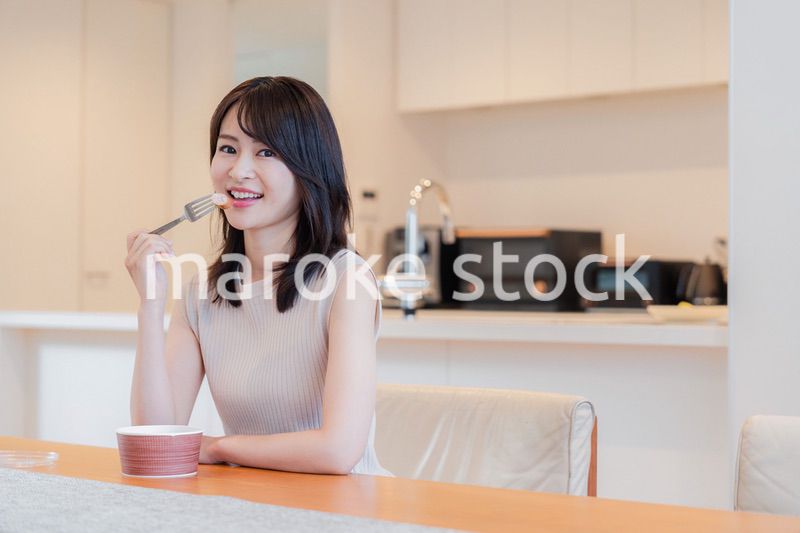 家でコンビニ弁当を食べる若い女性