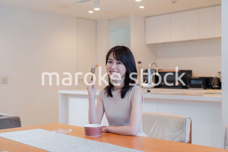 家でコンビニ弁当を食べる若い女性