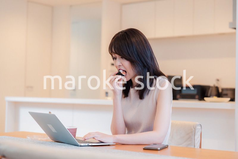 テレワークをしながらごはんを食べる多忙な女性