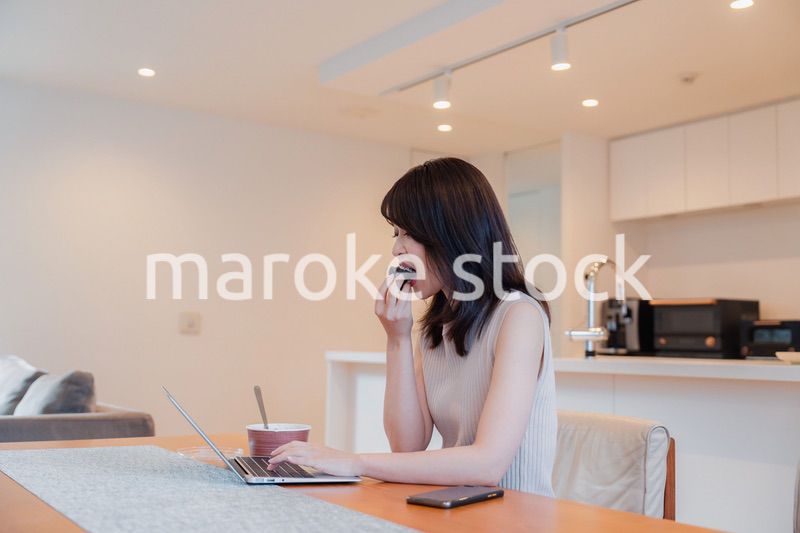 テレワークをしながらごはんを食べる多忙な女性