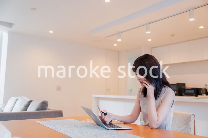 テレワークをしながらごはんを食べる多忙な女性