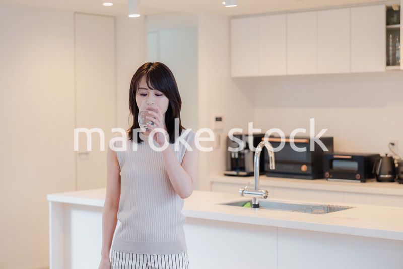 家で水を飲む若い女性