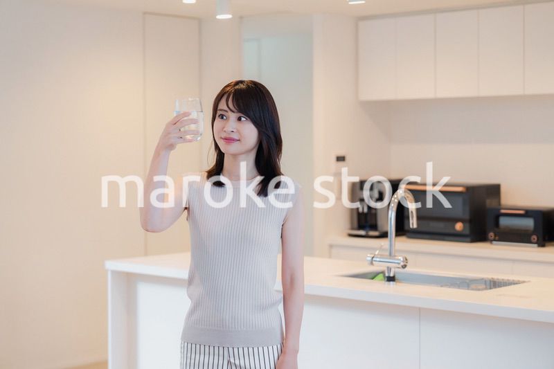 家で水を飲む若い女性