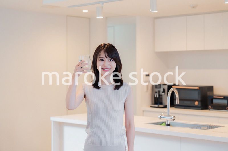 家で水を飲む若い女性