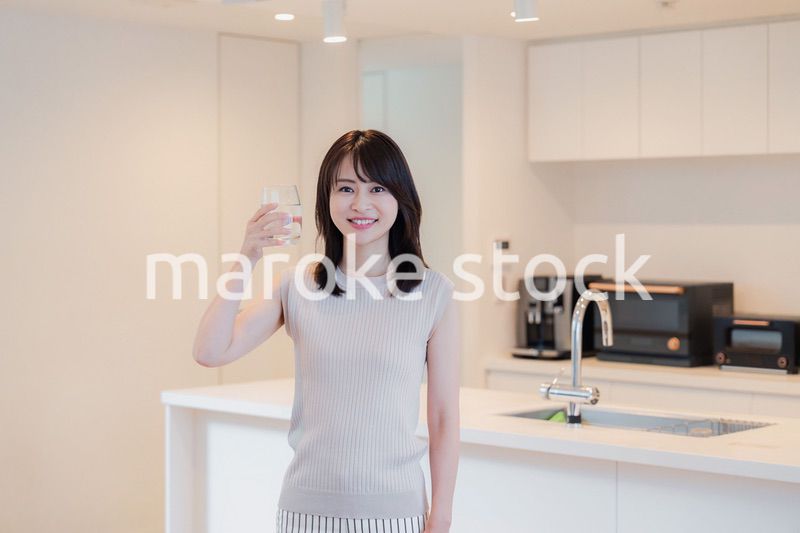 家で水を飲む若い女性