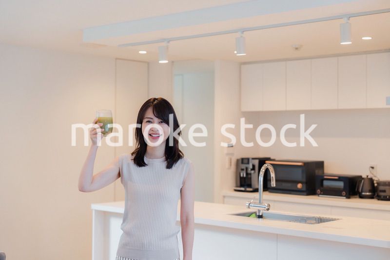 家でスムージーを飲む若い女性