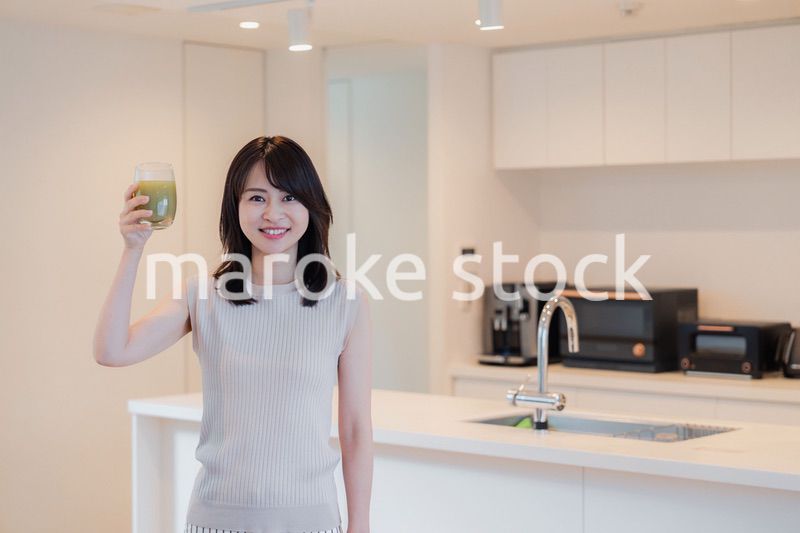 家でスムージーを飲む若い女性