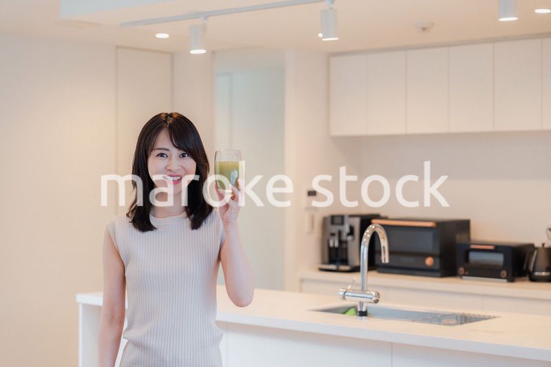 家でスムージーを飲む若い女性