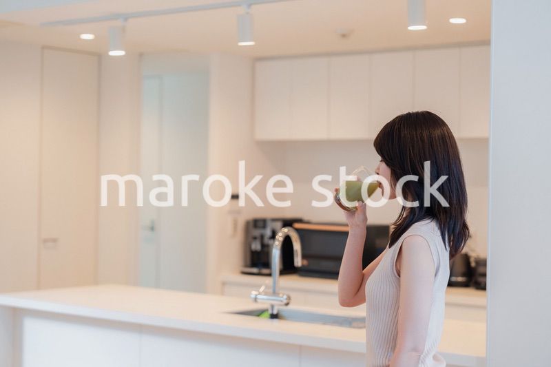 家でスムージーを飲む若い女性