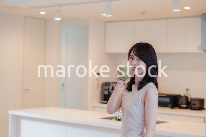 家でスムージーを飲む若い女性