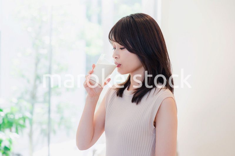 家でミルクを飲む若い女性