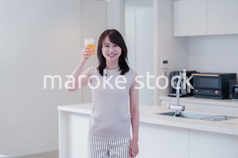 家事をしながらアルコールを飲む若い女性