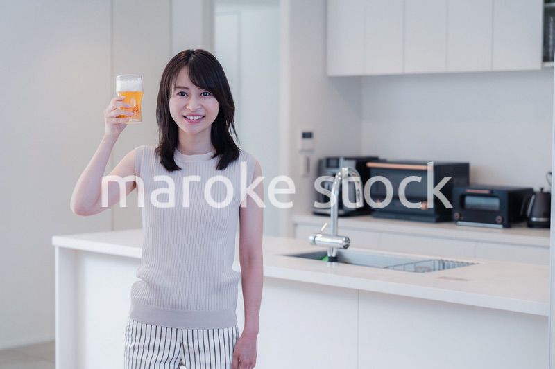 家事をしながらアルコールを飲む若い女性