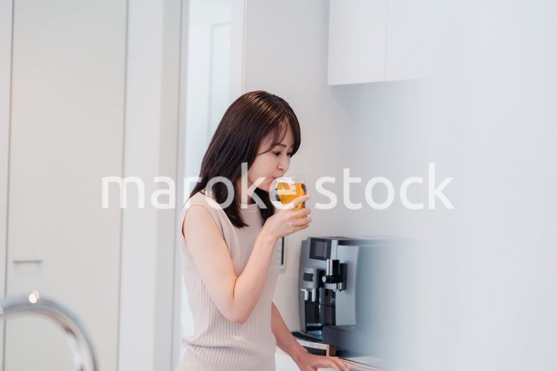 家事をしながらアルコールを飲む若い女性