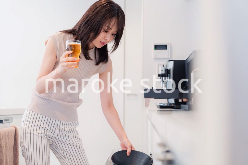 家事をしながらアルコールを飲む若い女性