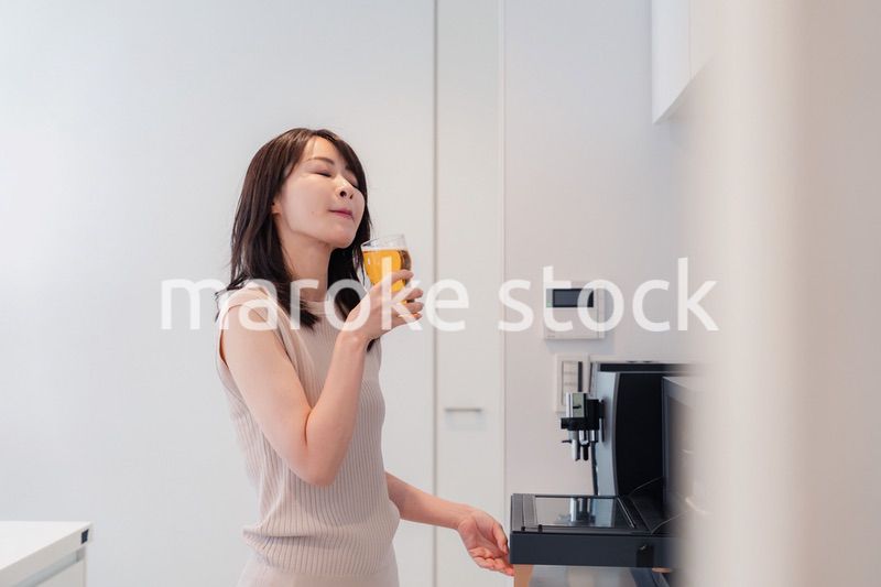 家事をしながらアルコールを飲む若い女性