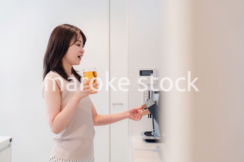 家事をしながらアルコールを飲む若い女性