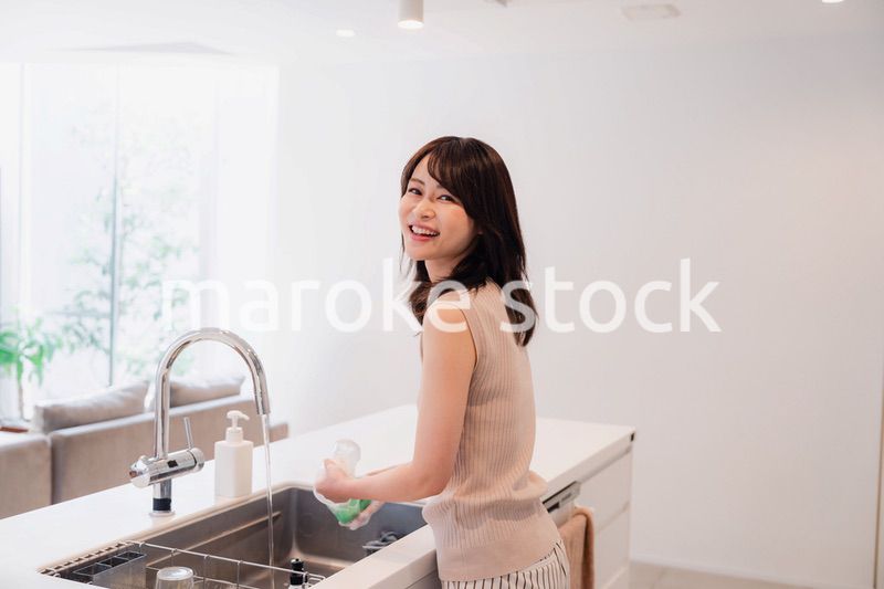 キッチンで洗い物をする若い女性