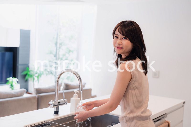 キッチンで洗い物をする若い女性