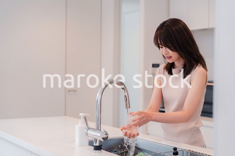 キッチンで洗い物をする若い女性