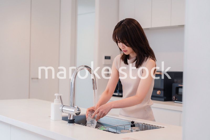 キッチンで洗い物をする若い女性