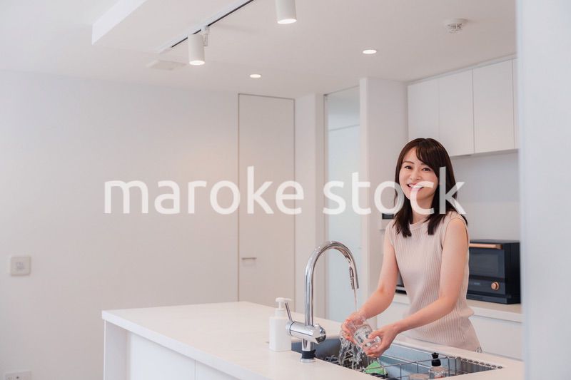 キッチンで洗い物をする若い女性