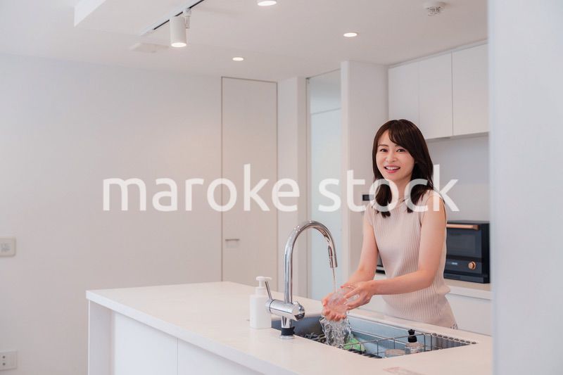 キッチンで洗い物をする若い女性