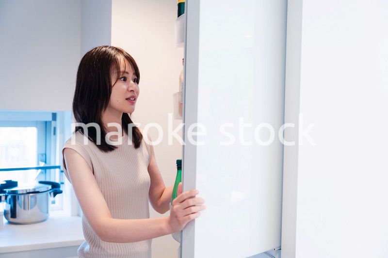 冷蔵庫を開けて物を取り出す若い女性