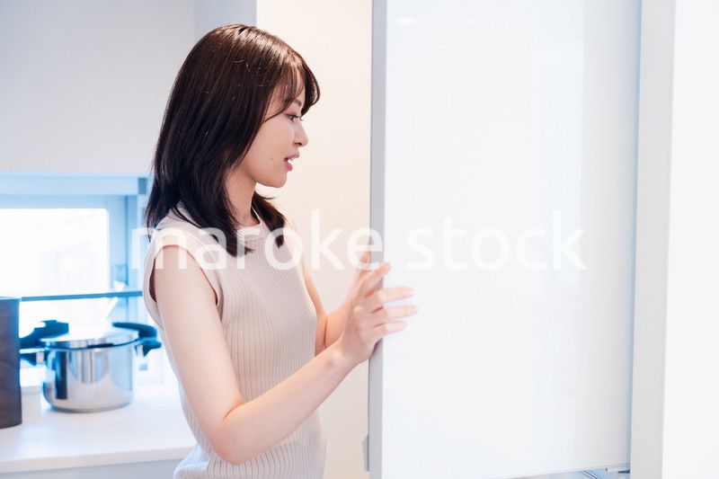 冷蔵庫を開けて物を取り出す若い女性