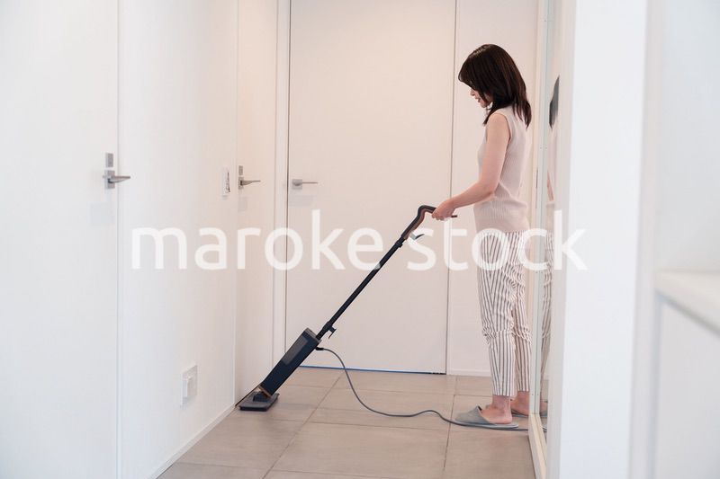 掃除機で家の掃除をする若い女性