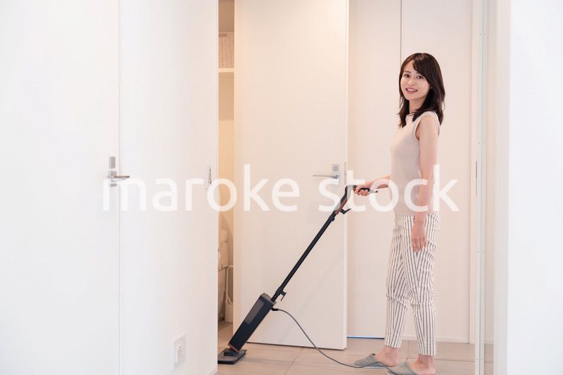 掃除機で家の掃除をする若い女性