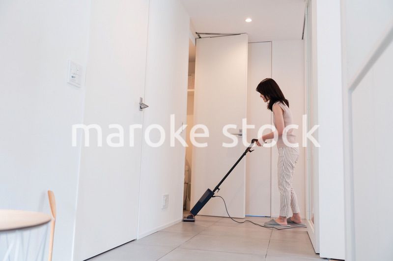 掃除機で家の掃除をする若い女性