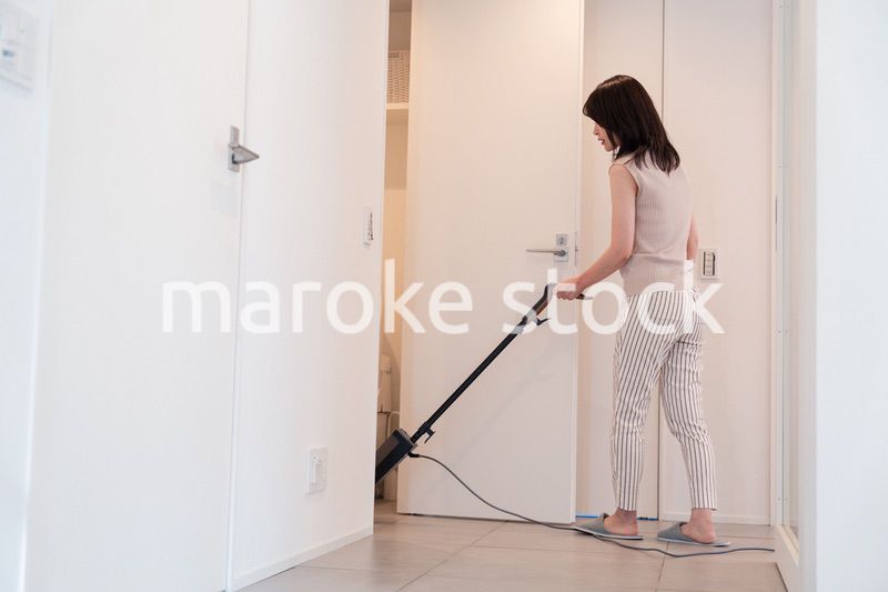 掃除機で家の掃除をする若い女性