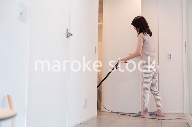 掃除機で家の掃除をする若い女性