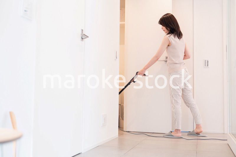 掃除機で家の掃除をする若い女性