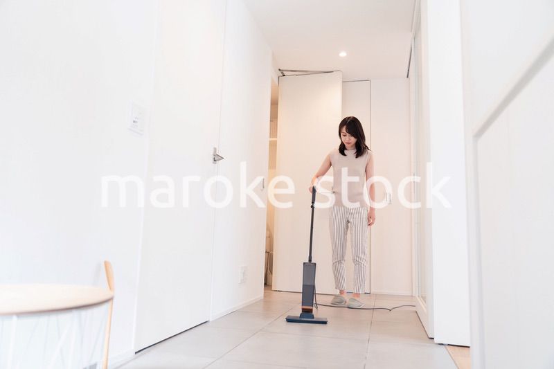 掃除機で家の掃除をする若い女性