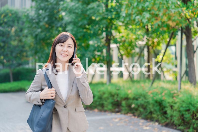 電話で話しながらビジネス街を歩くビジネスウーマン