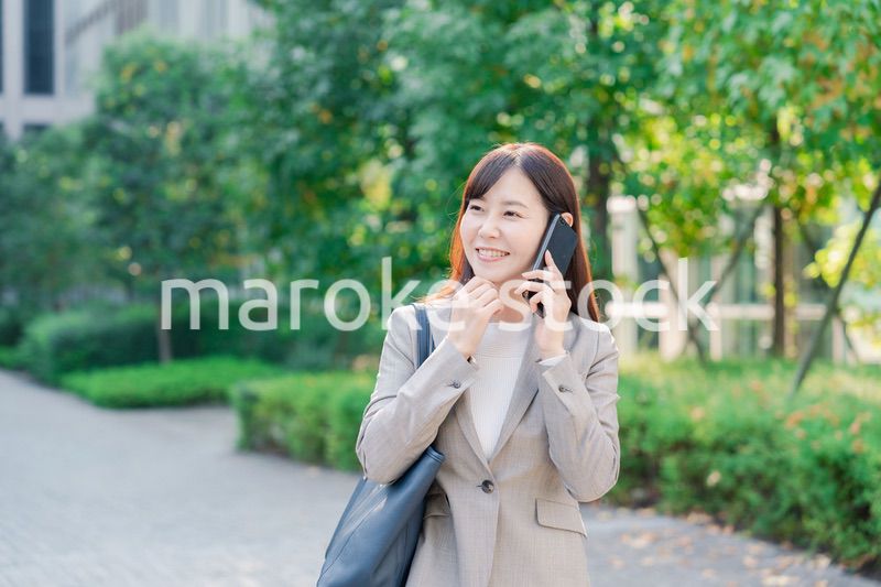 電話で話しながらビジネス街を歩くビジネスウーマン