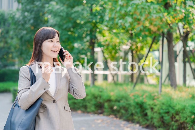 電話で話しながらビジネス街を歩くビジネスウーマン