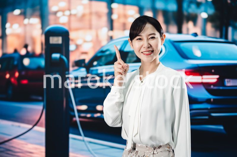 道路で電気自動車を充電する女性