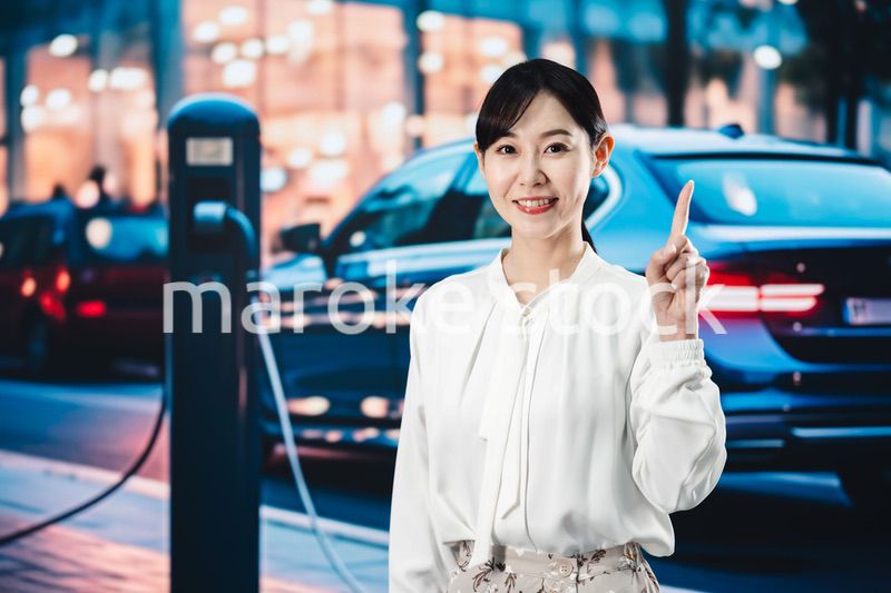 道路で電気自動車を充電する女性
