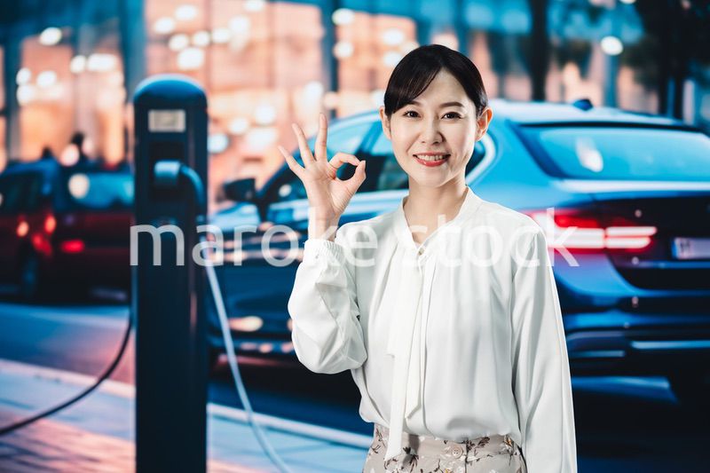 道路で電気自動車を充電する女性
