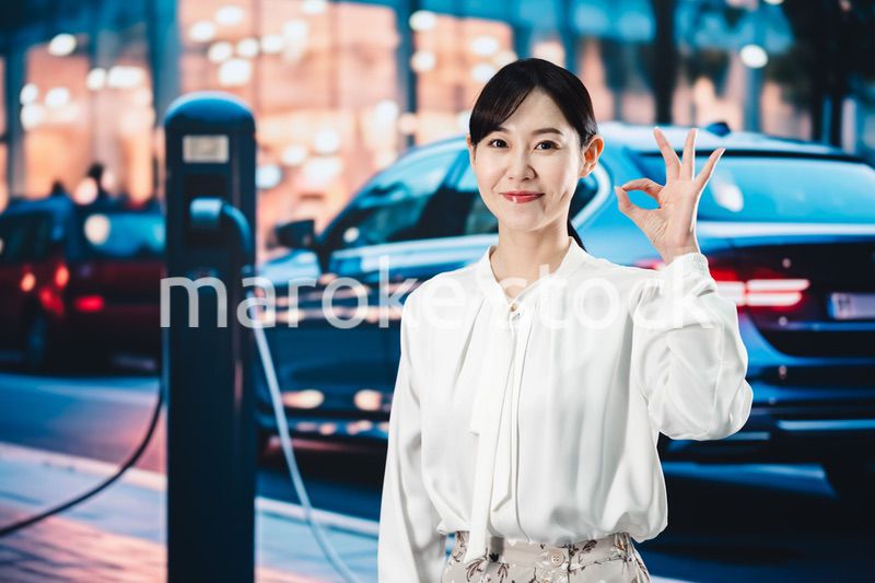 道路で電気自動車を充電する女性