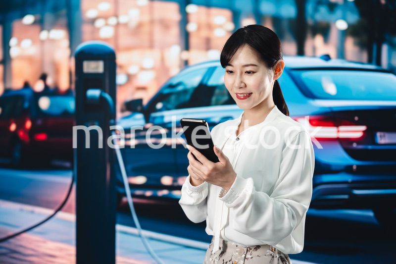 道路で電気自動車を充電する女性