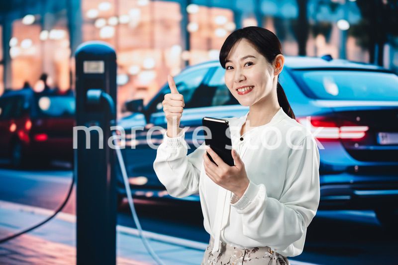 道路で電気自動車を充電する女性