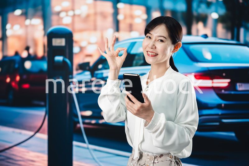 道路で電気自動車を充電する女性